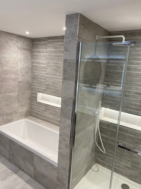 Illuminated alcove on textured feature wall with matt white brassware, extractable shower handset, and overhead showerhead in luxury bathroom