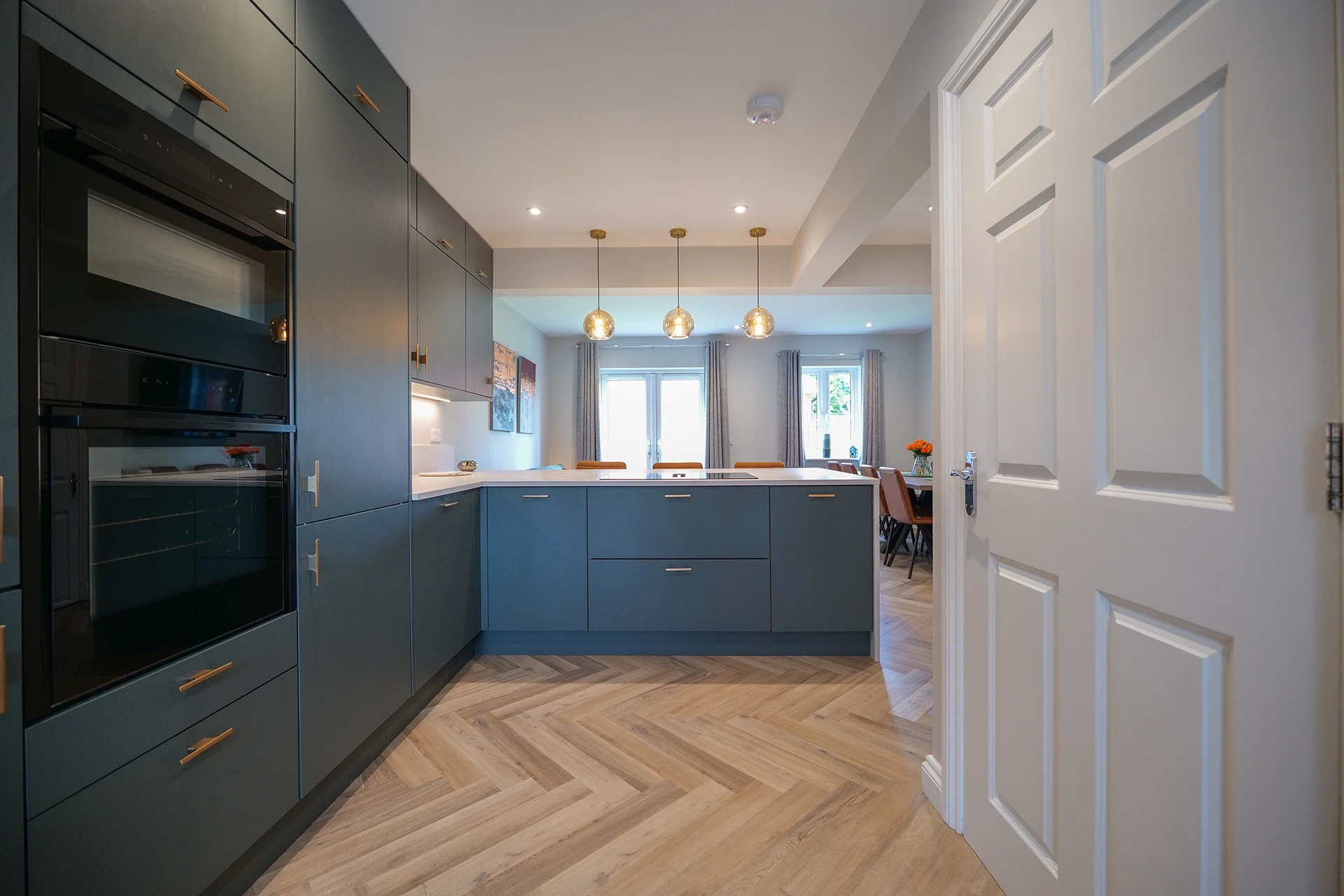 Contemporary Masterclass kitchen featuring sleek cabinetry and three stylish pendant lights over the breakfast bar.