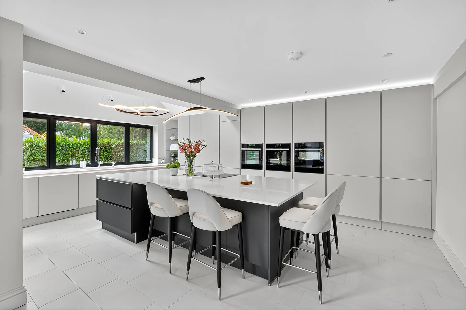 Häcker kitchen with soft taupe gloss cabinetry and graphite island, finished with quartz worktops and Neff appliances