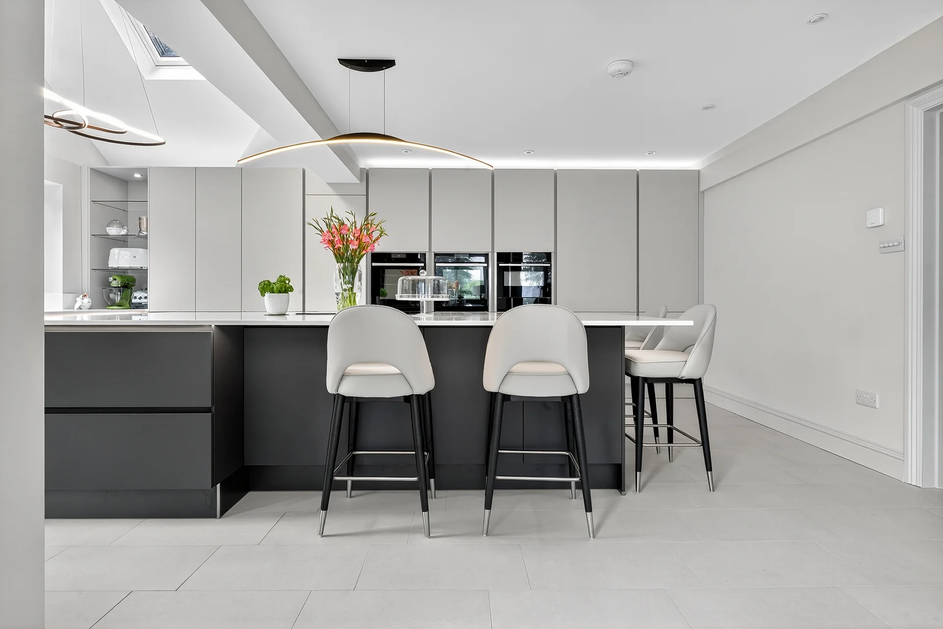 Häcker kitchen, soft taupe gloss cabinetry and graphite island, finished with quartz worktops