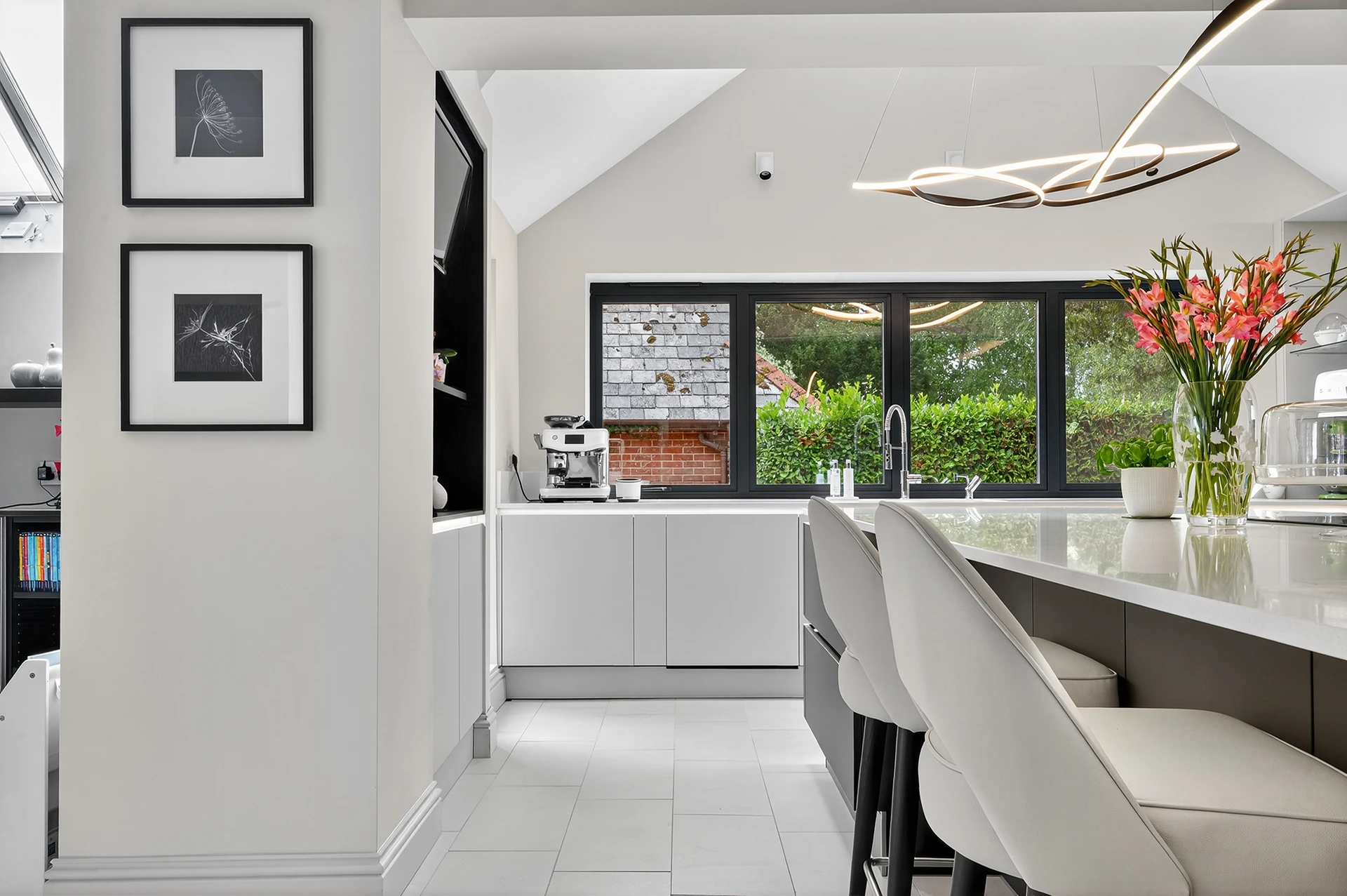 Modern Häcker kitchen featuring soft taupe gloss doors, graphite island unit and sleek quartz worktops with integrated Neff appliances