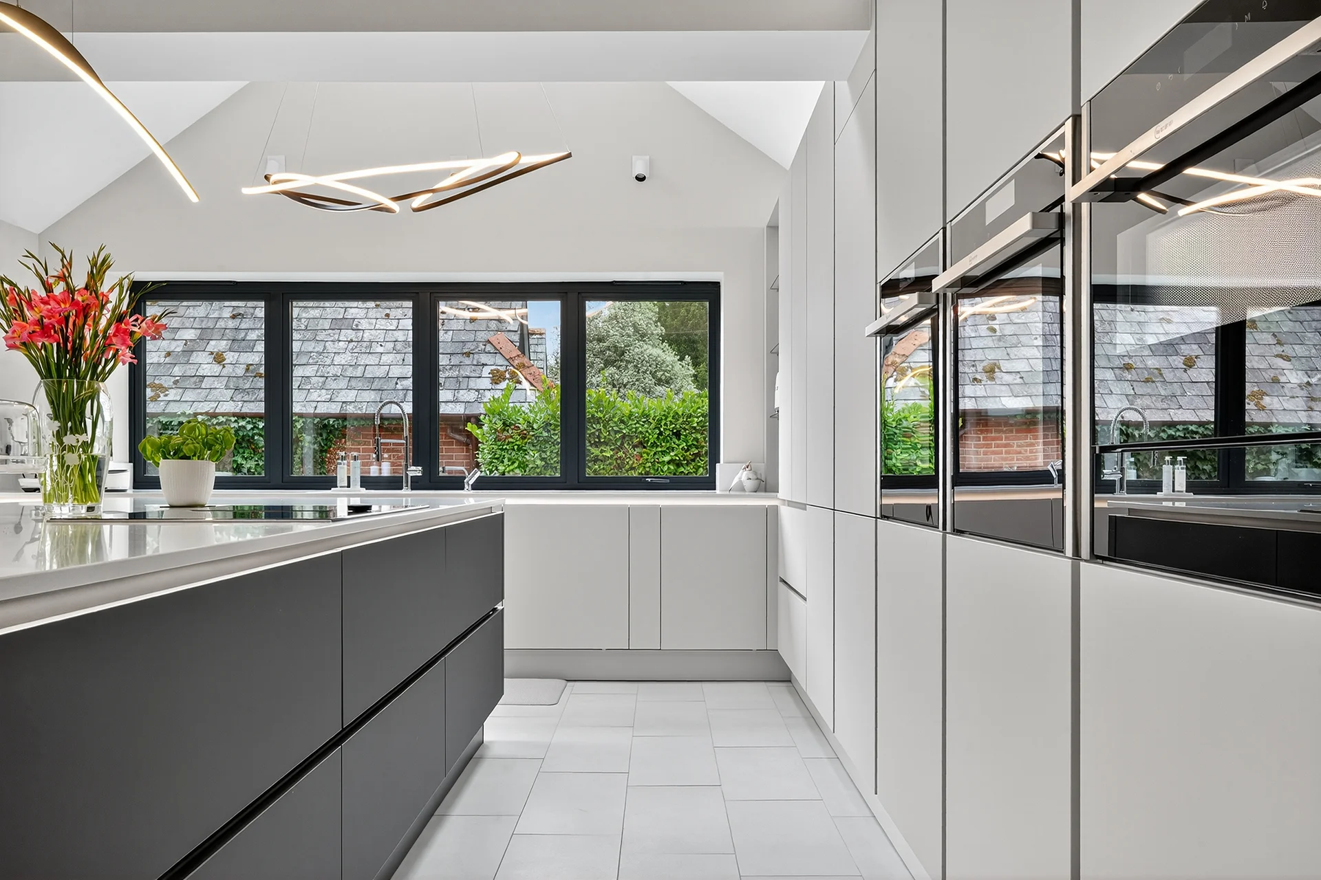 Contemporary Häcker kitchen design with taupe gloss units, contrasting graphite island and premium quartz surfaces