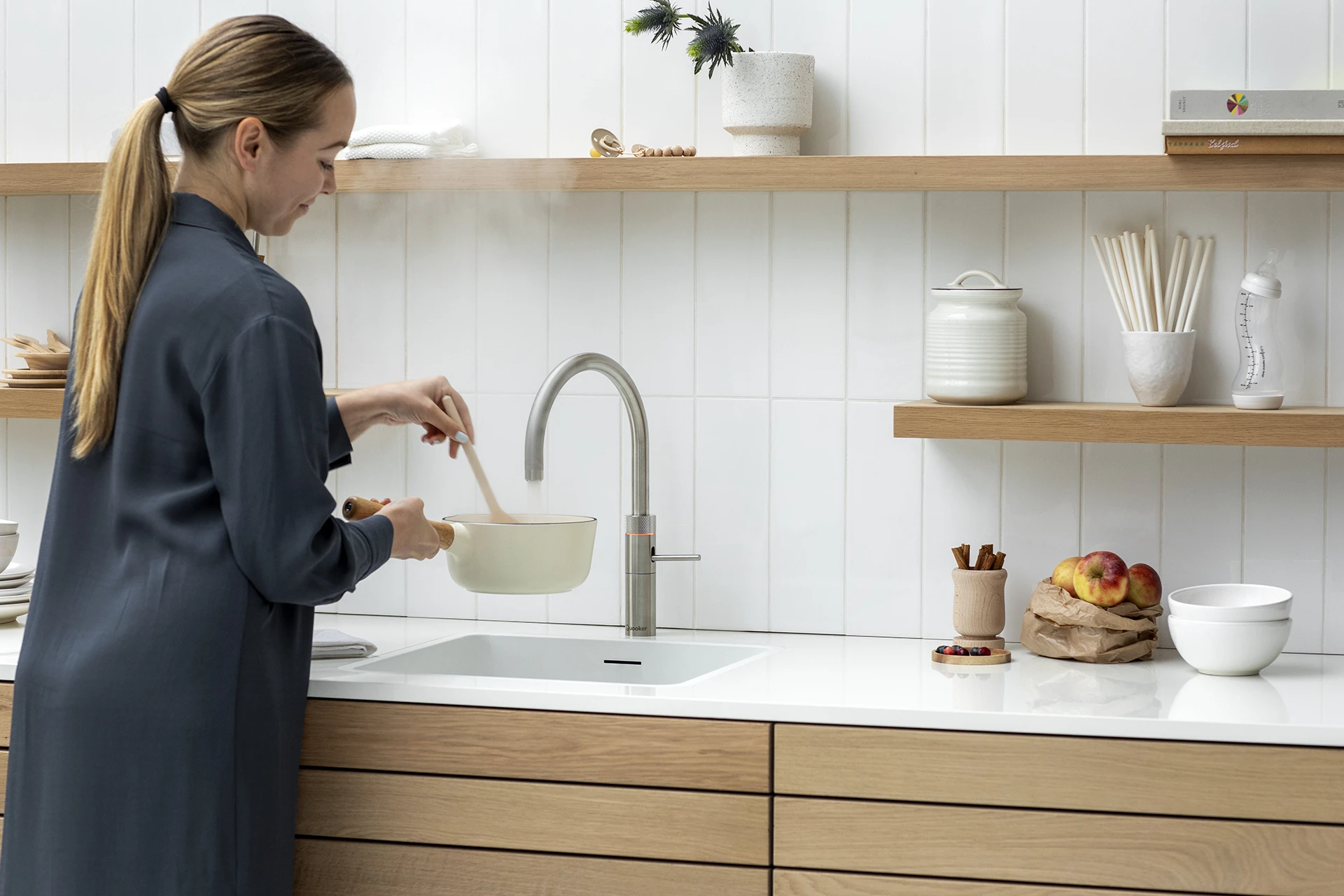 A woman using a Fusion Round Stainless Steel Quooker tap